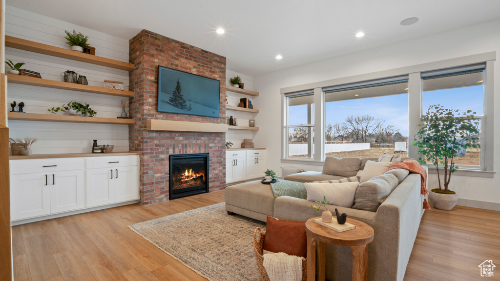 Living room with a fireplace, light hardwood / wood-style flooring, and brick wall