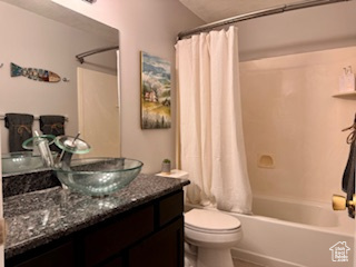 Full bathroom with shower / tub combo, toilet, and large vanity
