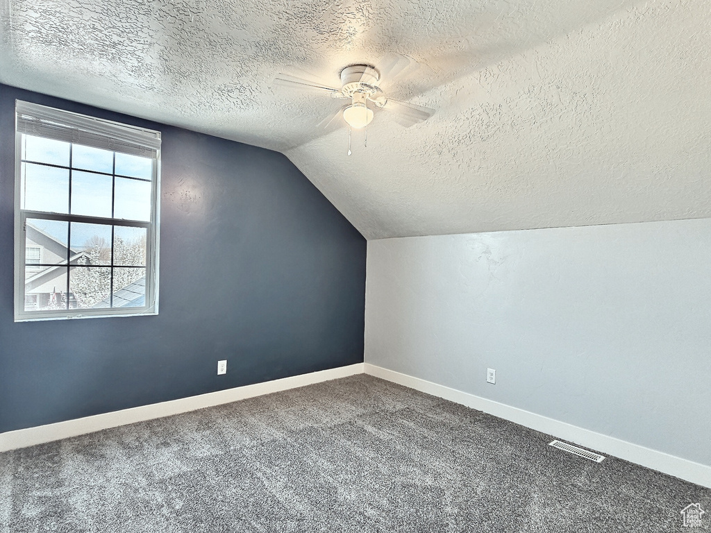 Bonus room with a textured ceiling, ceiling fan, lofted ceiling, and carpet flooring