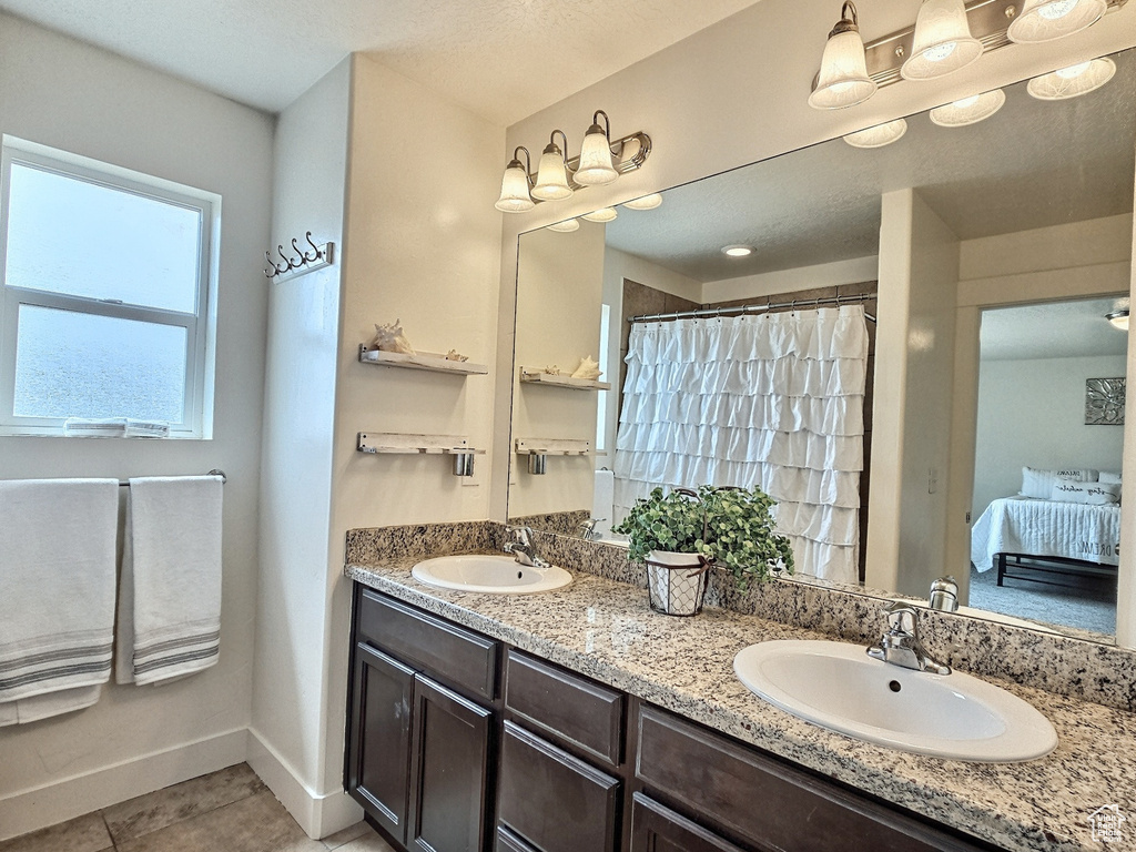 Bathroom with vanity with extensive cabinet space, double sink, and tile flooring