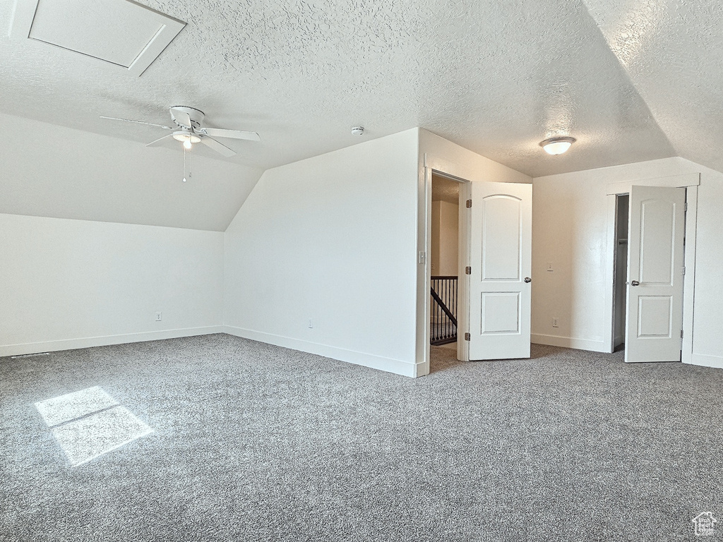 Bonus room featuring a textured ceiling, ceiling fan, carpet floors, and lofted ceiling