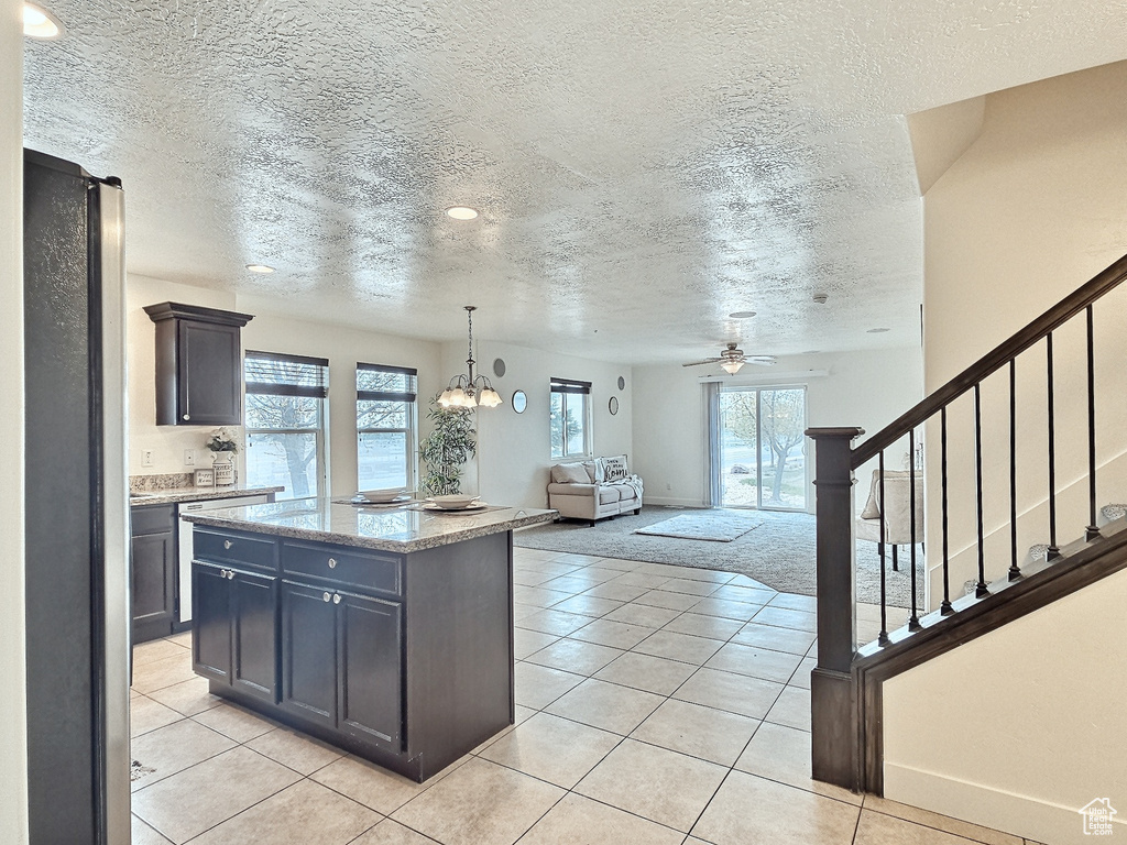 Kitchen featuring a wealth of natural light, hanging light fixtures, a center island, and light tile flooring