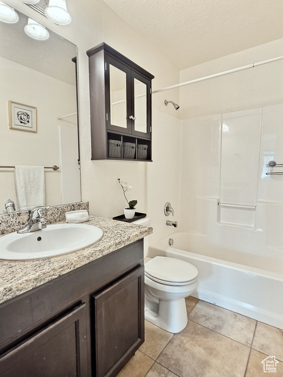 Full bathroom with vanity with extensive cabinet space, tile floors, toilet, washtub / shower combination, and a textured ceiling