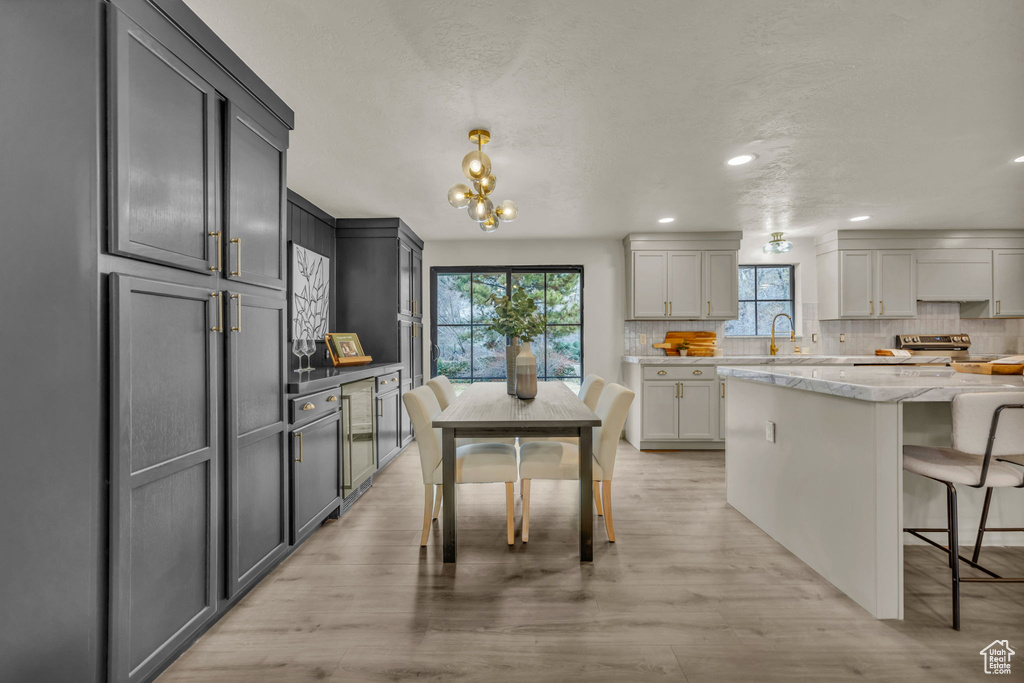 Kitchen with light wood-type flooring, an inviting chandelier, backsplash, and gray cabinetry
