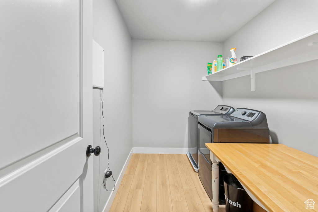 Laundry area with light hardwood / wood-style flooring and washing machine and dryer