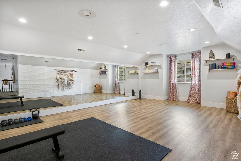 Workout area featuring light hardwood / wood-style floors and vaulted ceiling