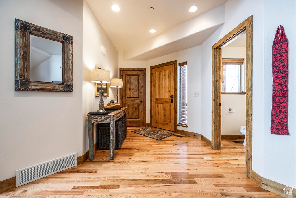Foyer entrance with light hardwood / wood-style floors and vaulted ceiling