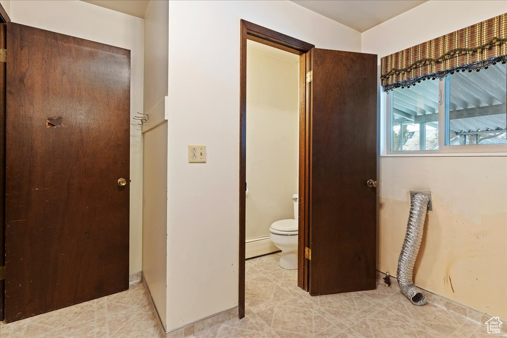 Bathroom with baseboard heating, tile floors, and toilet