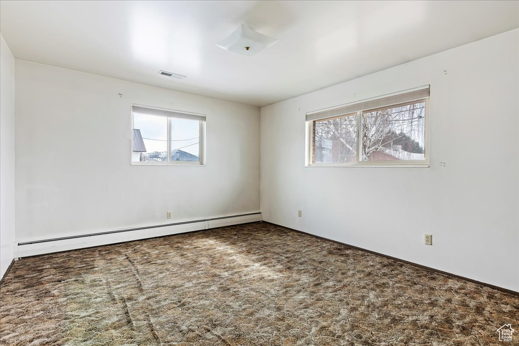 Carpeted spare room featuring baseboard heating