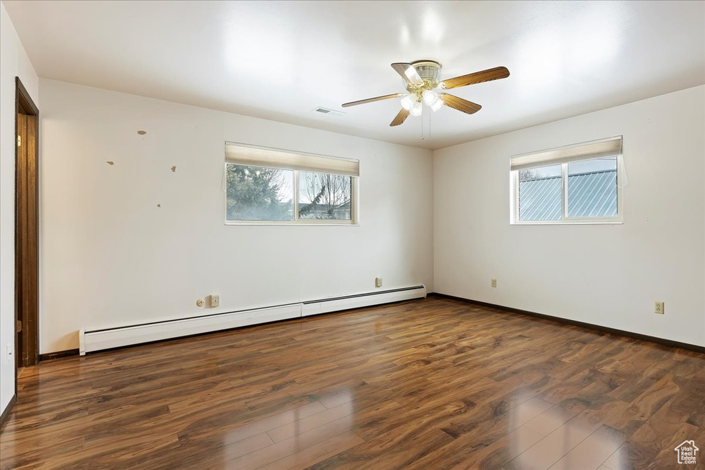 Spare room with a baseboard radiator, dark wood-type flooring, and ceiling fan