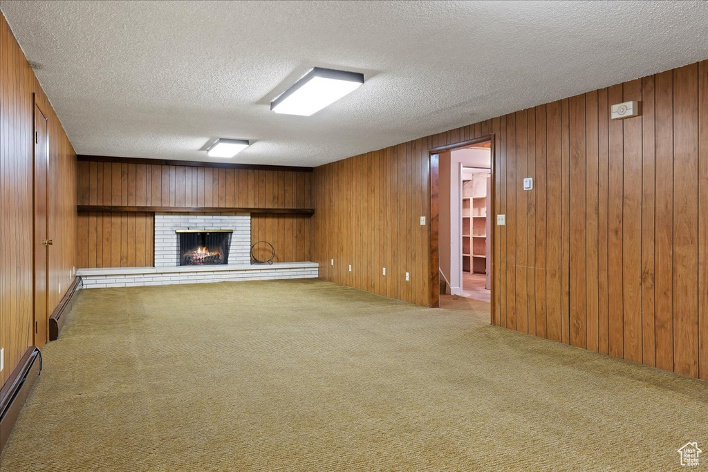 Unfurnished living room with wooden walls, a brick fireplace, and light colored carpet