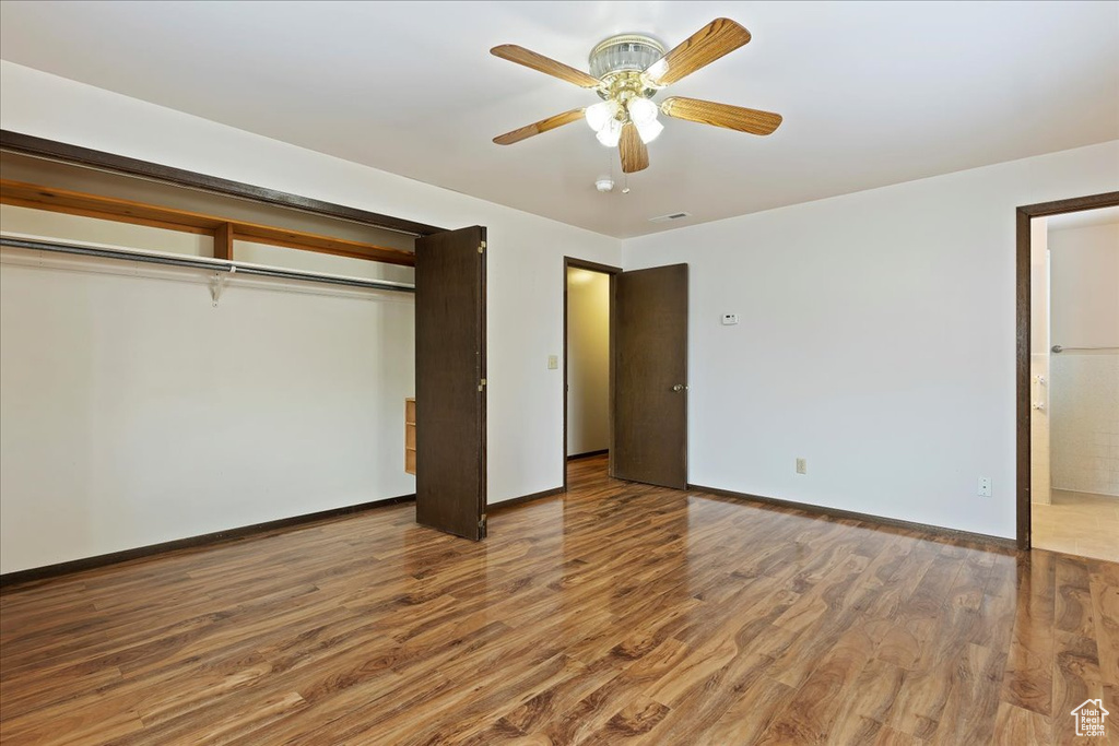Unfurnished bedroom featuring hardwood / wood-style floors, a closet, and ceiling fan
