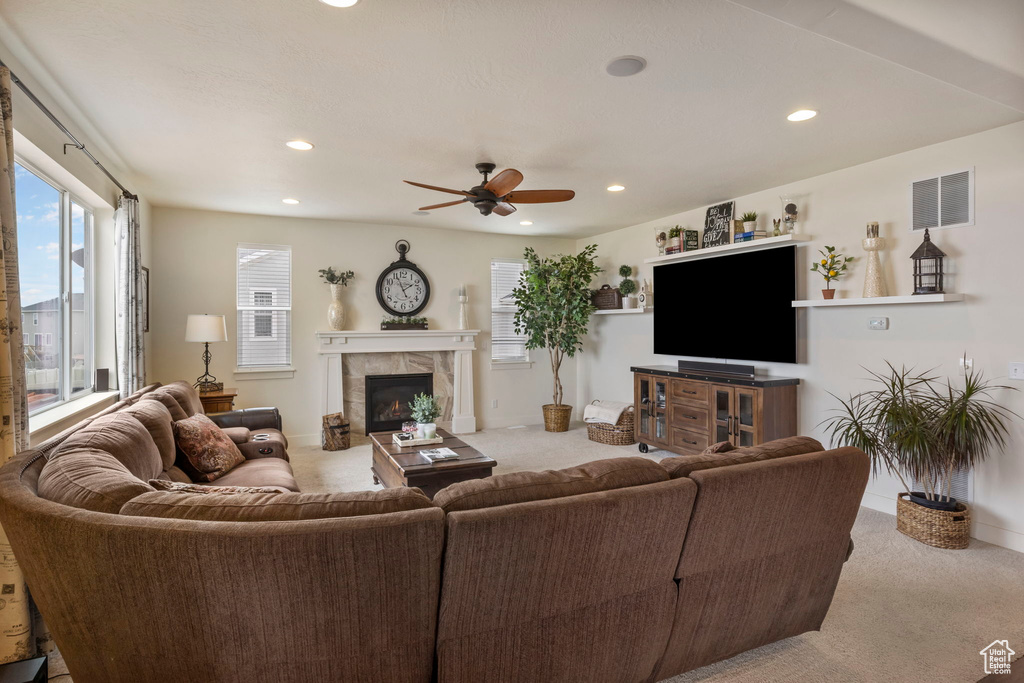 Carpeted living room featuring ceiling fan and a tiled fireplace