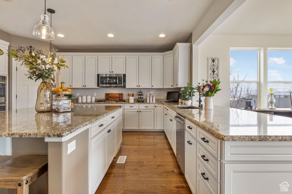 Kitchen featuring light hardwood / wood-style floors, light stone countertops, white cabinetry, sink, and appliances with stainless steel finishes