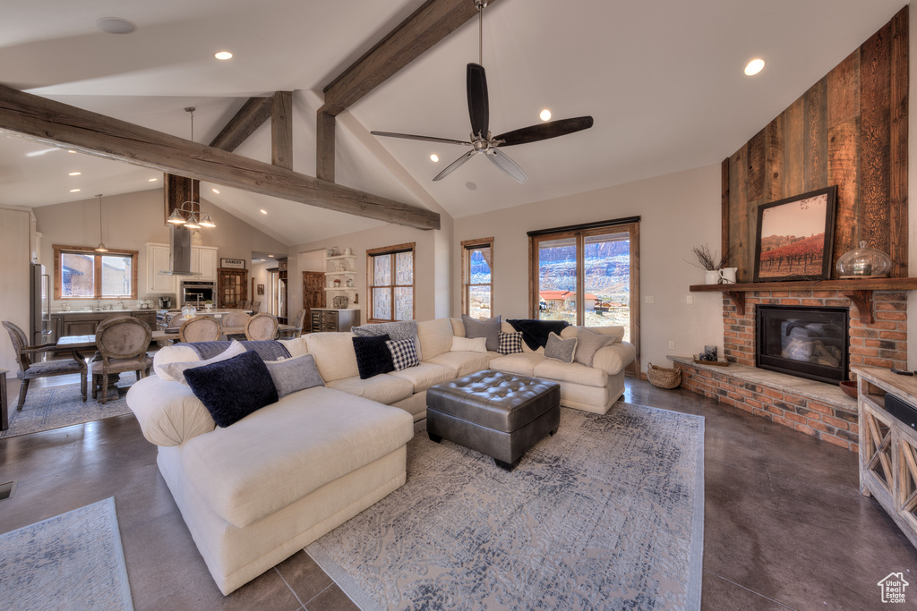 Living room with wood walls, ceiling fan, a brick fireplace, high vaulted ceiling, and beam ceiling