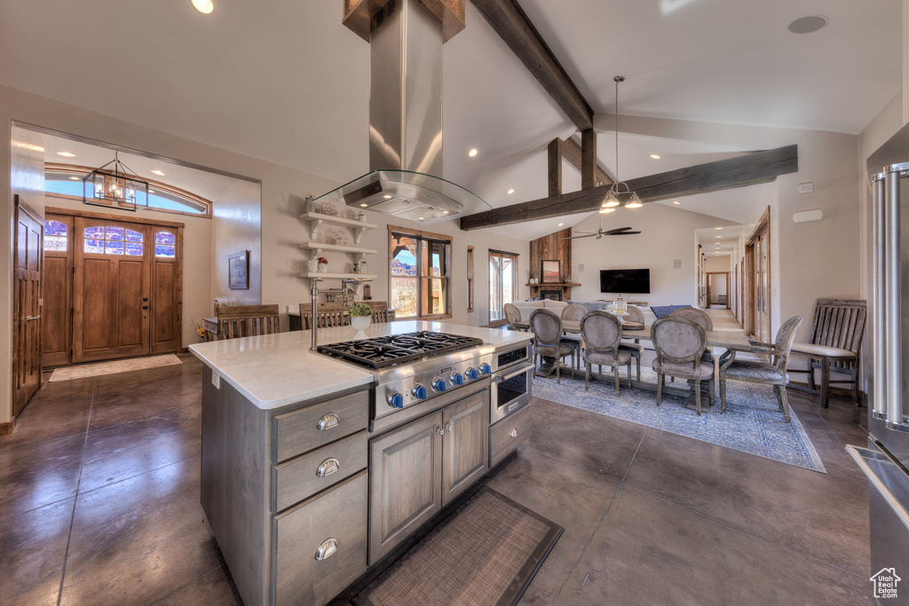 Kitchen featuring a center island, island exhaust hood, ceiling fan with notable chandelier, cooktop, and beam ceiling