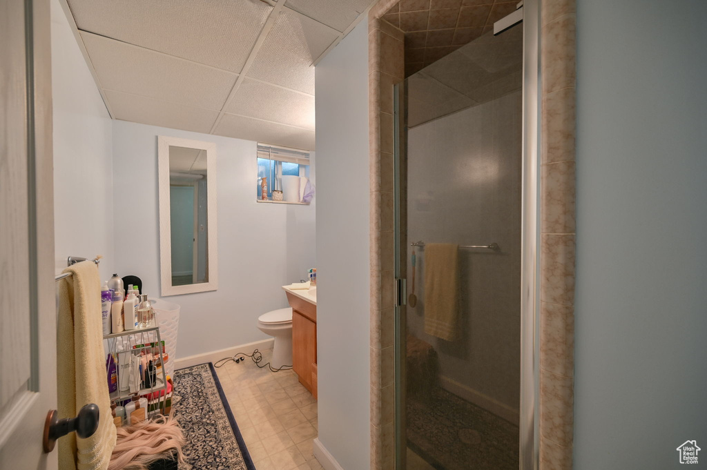 Bathroom with a shower with door, large vanity, a paneled ceiling, and toilet