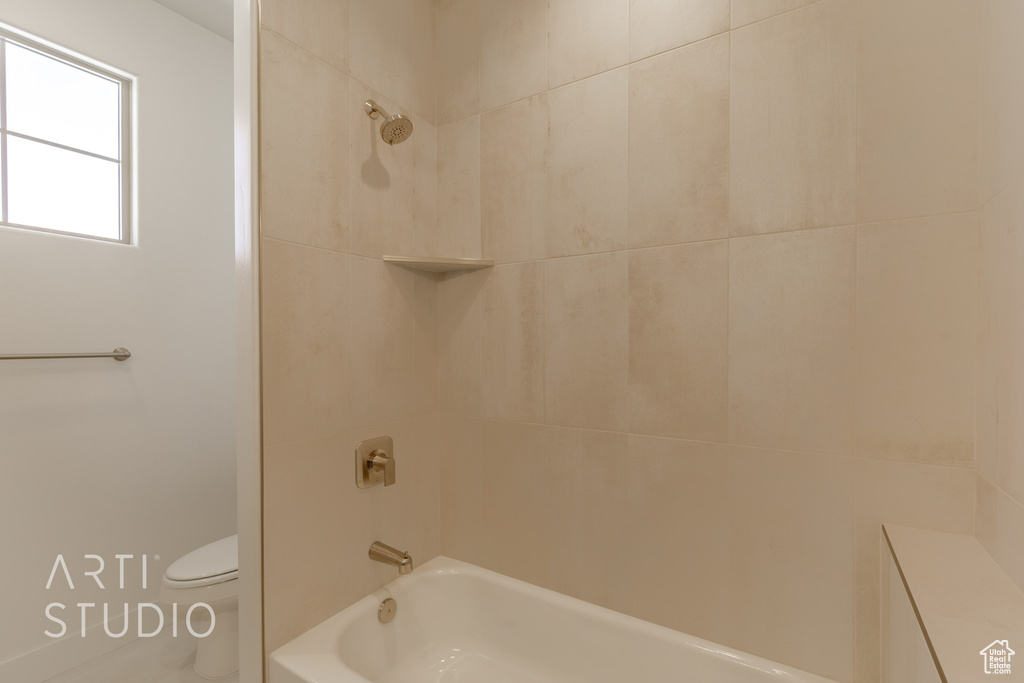 Bathroom featuring tiled shower / bath combo and toilet