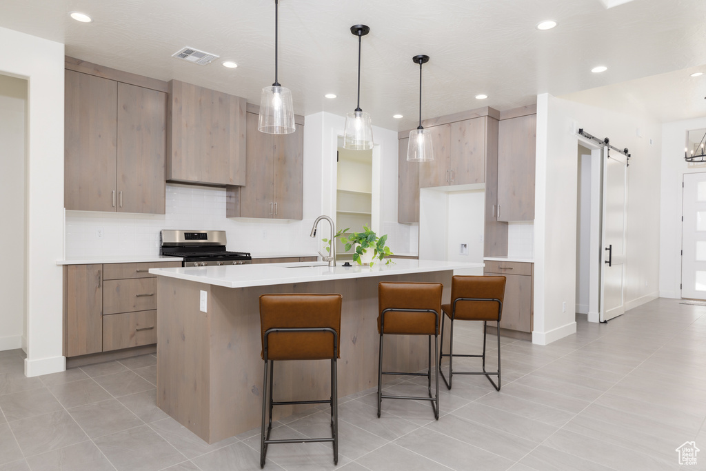 Kitchen with light tile patterned floors, a barn door, sink, and a breakfast bar