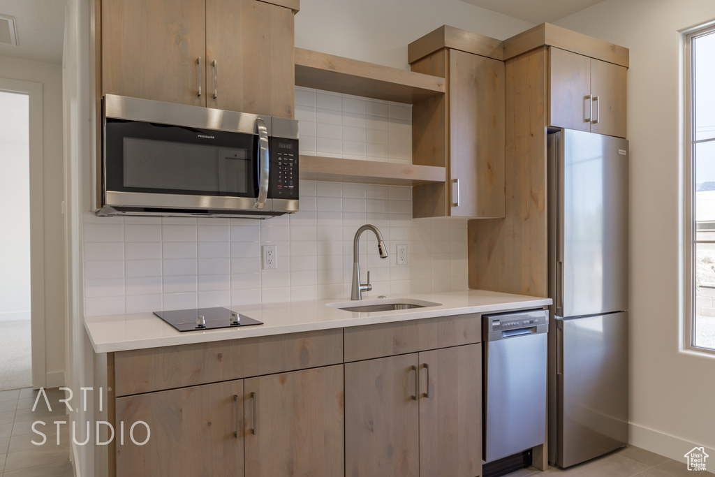 Kitchen featuring light tile patterned floors, backsplash, sink, and stainless steel appliances