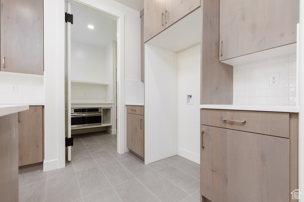 Kitchen featuring light tile patterned floors, tasteful backsplash, and oven