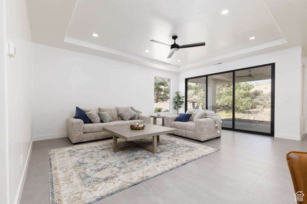 Tiled living room featuring ceiling fan and a raised ceiling