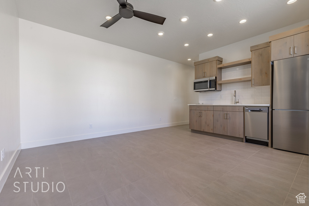 Kitchen with appliances with stainless steel finishes, light brown cabinetry, tasteful backsplash, ceiling fan, and light tile patterned floors