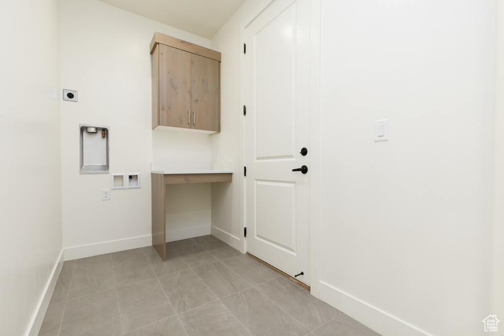 Washroom with cabinets, light tile patterned flooring, hookup for an electric dryer, and hookup for a washing machine