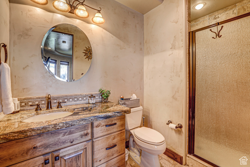 Bathroom with toilet, a shower with shower door, tile floors, and oversized vanity