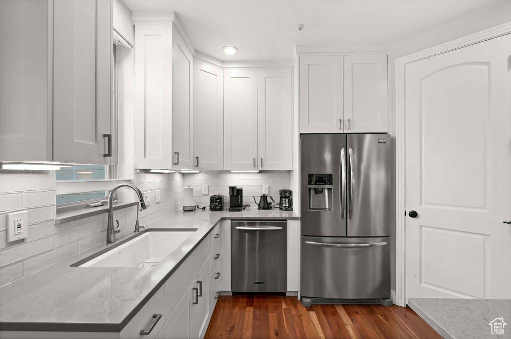 Kitchen with white cabinets, appliances with stainless steel finishes, and dark wood-type flooring