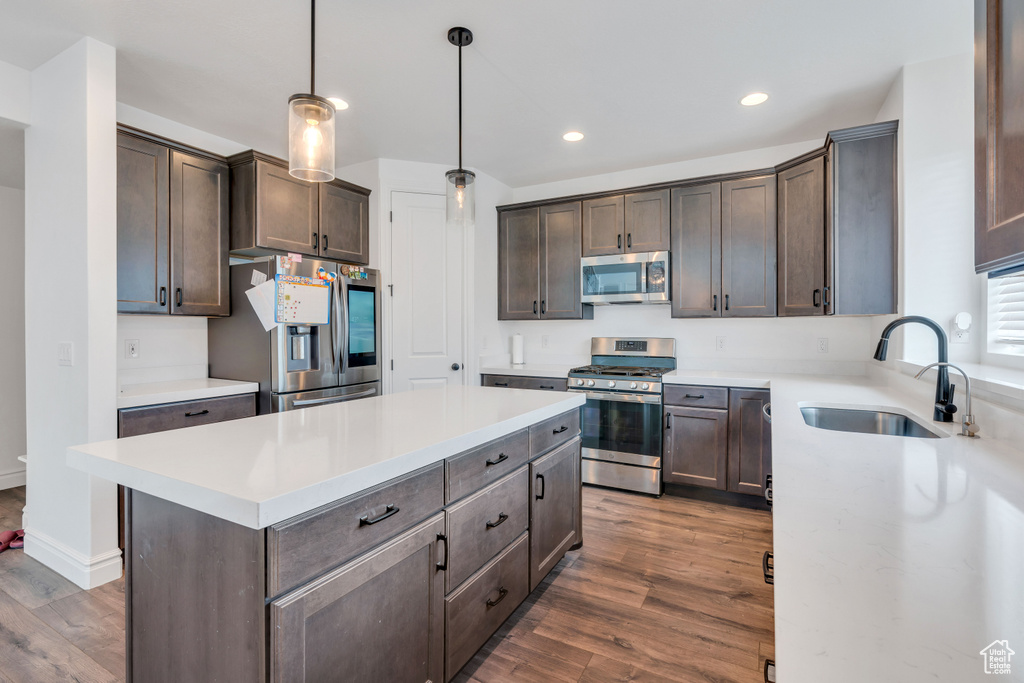 Kitchen with a center island, dark hardwood / wood-style flooring, sink, stainless steel appliances, and pendant lighting