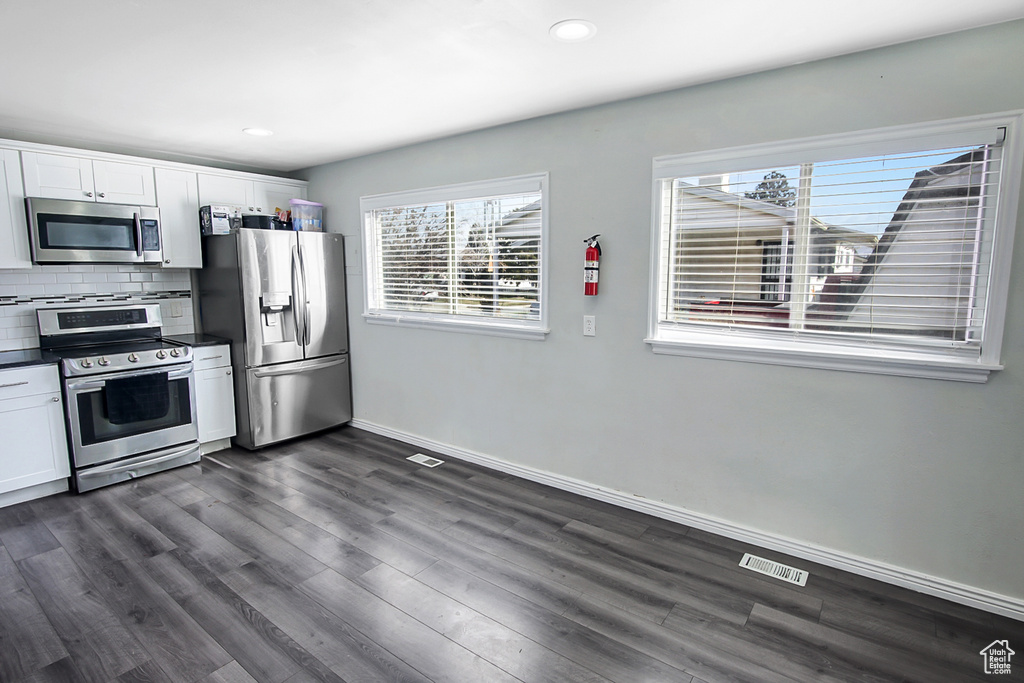 Kitchen featuring tasteful backsplash, dark wood-type flooring, stainless steel appliances, and white cabinets