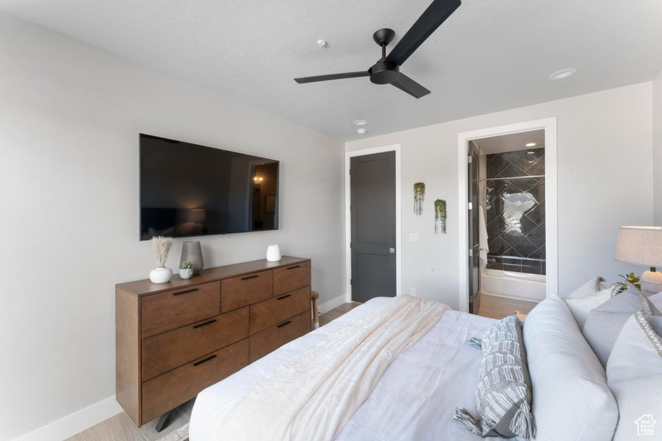 Bedroom with ensuite bath, light hardwood / wood-style flooring, and ceiling fan
