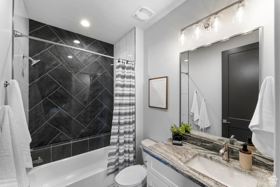 Full bathroom with shower / tub combo, oversized vanity, and toilet