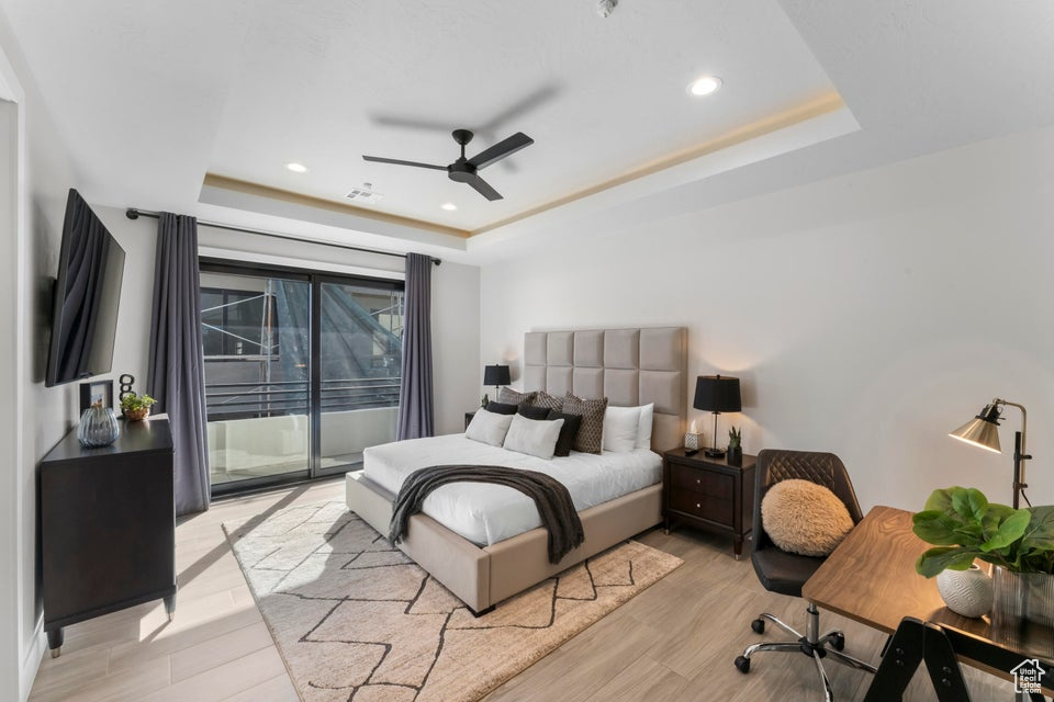 Bedroom with access to outside, a raised ceiling, ceiling fan, and light wood-type flooring