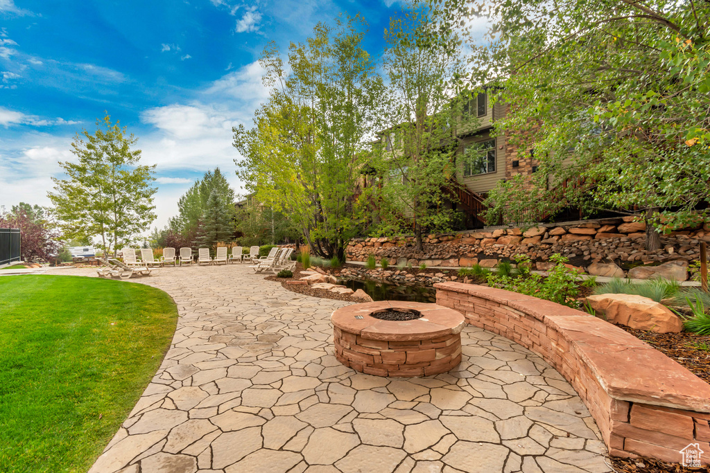 View of home\'s community featuring a lawn, a patio area, and a fire pit