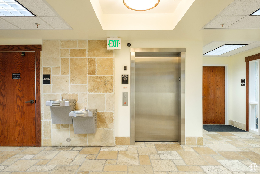 Bathroom with tile walls, a drop ceiling, elevator, and tile floors