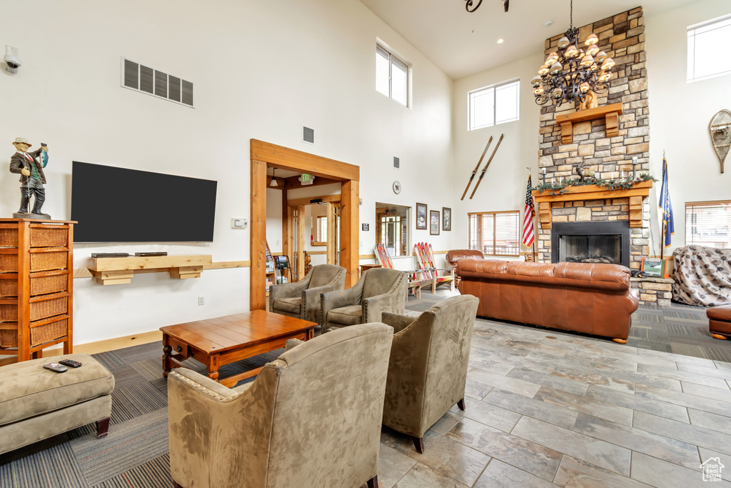 Living room with a high ceiling, a stone fireplace, and light tile floors