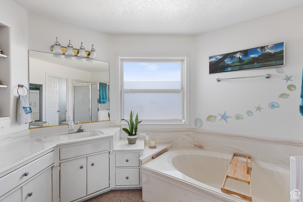 Bathroom with large vanity, separate shower and tub, and a textured ceiling