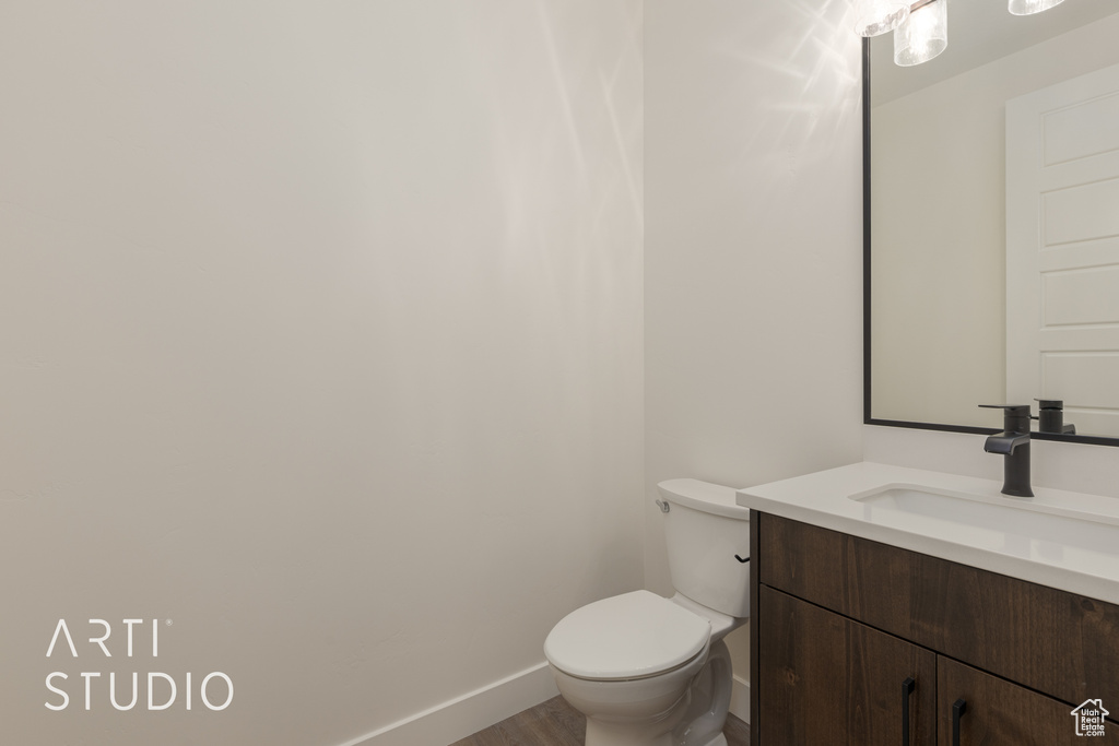 Bathroom with toilet, vanity, and hardwood / wood-style flooring