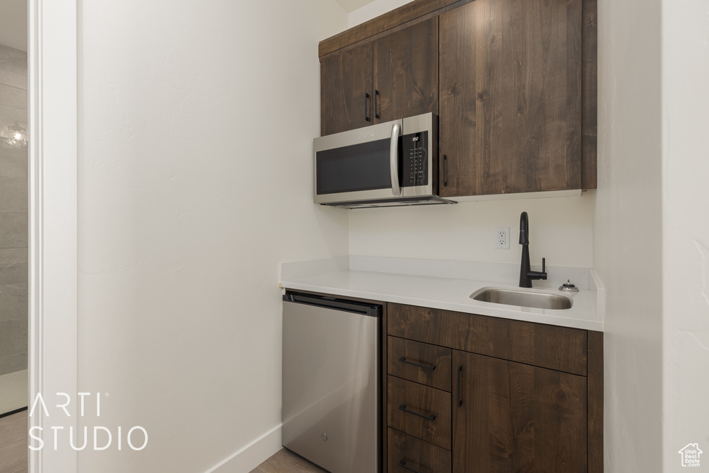 Kitchen featuring dark brown cabinets, fridge, and sink