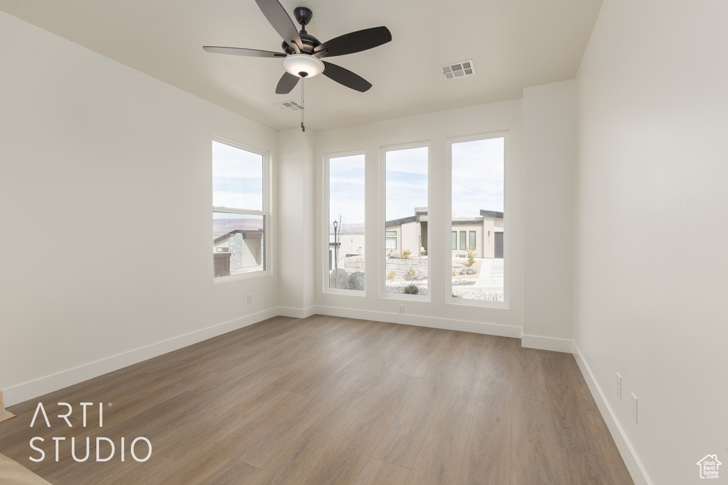 Unfurnished room with ceiling fan, light wood-type flooring, and a wealth of natural light