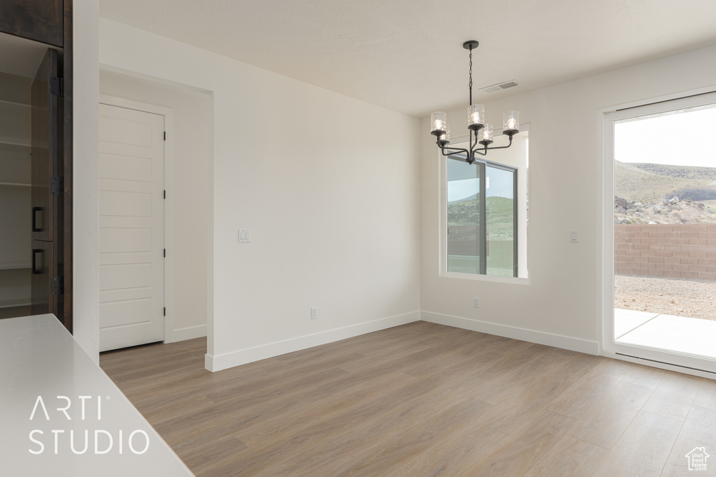 Unfurnished dining area featuring plenty of natural light, a chandelier, and light hardwood / wood-style flooring