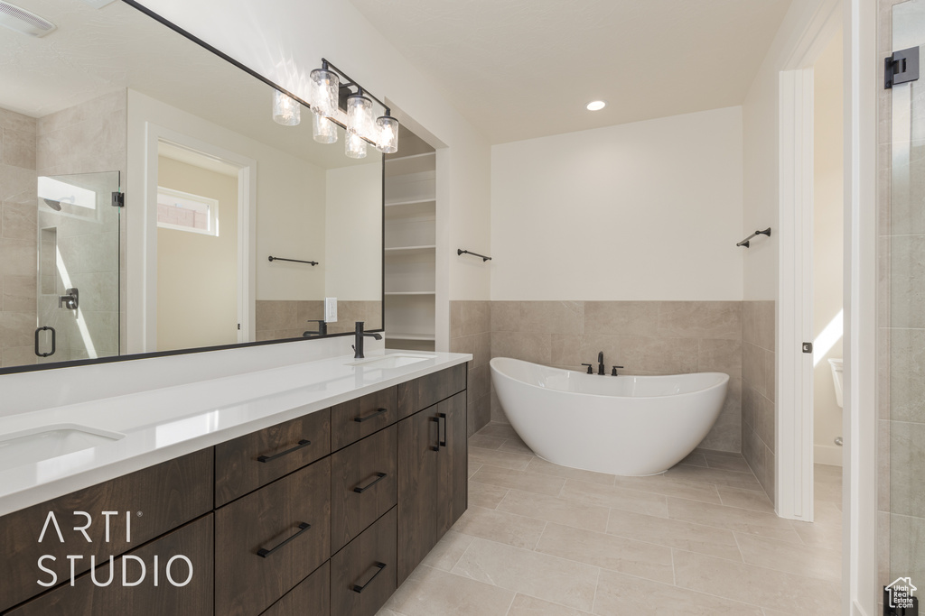 Bathroom featuring tile walls, tile floors, a shower with shower door, and double sink vanity