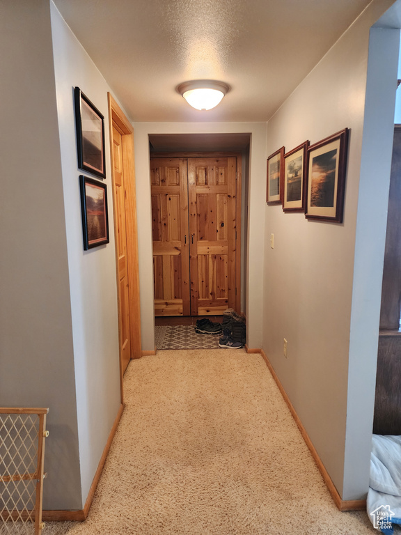 Hallway featuring light carpet and a textured ceiling
