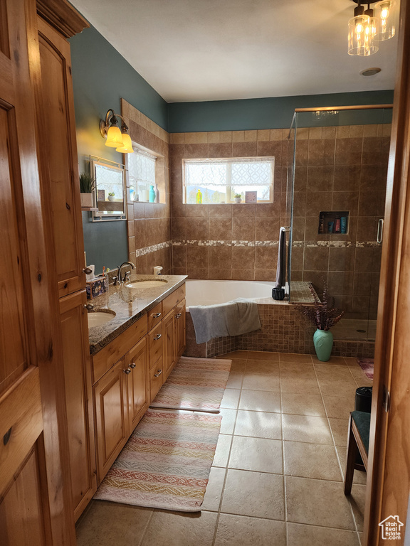 Bathroom with a notable chandelier, plus walk in shower, tile floors, double sink, and vanity with extensive cabinet space