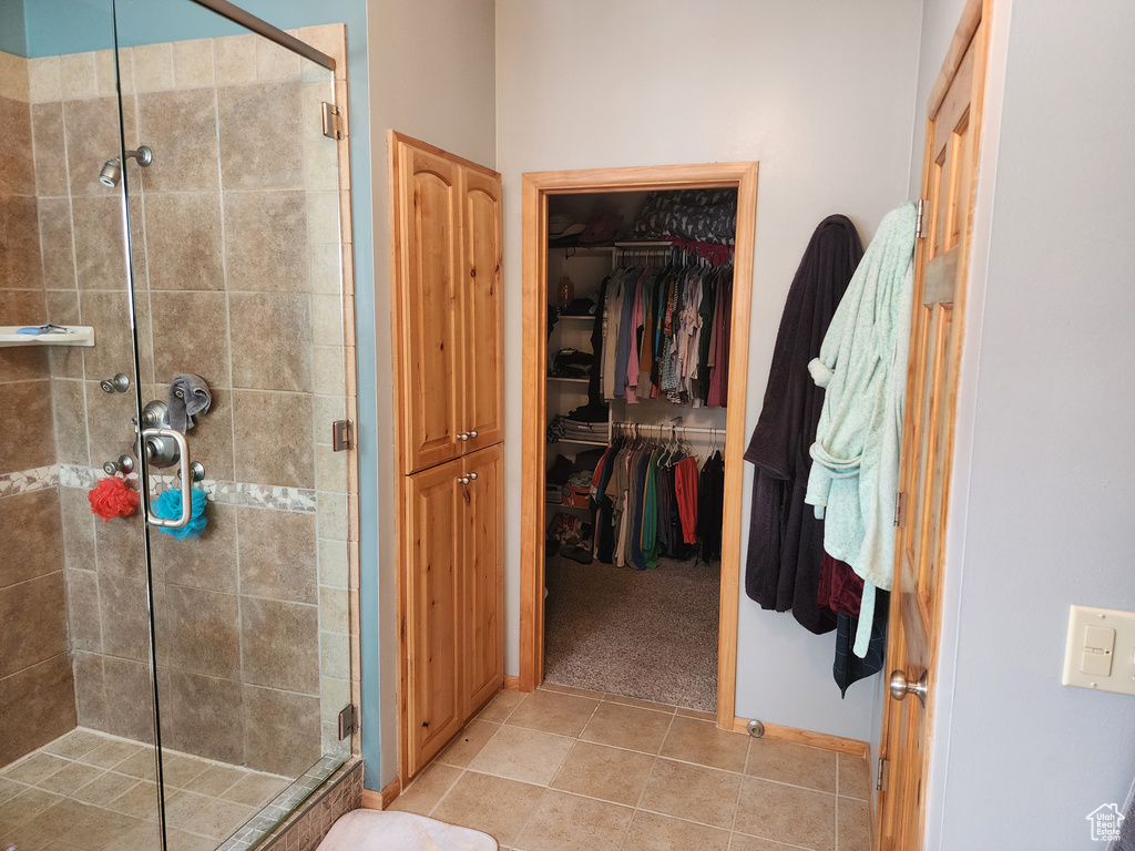 Bathroom with a shower with door and tile flooring