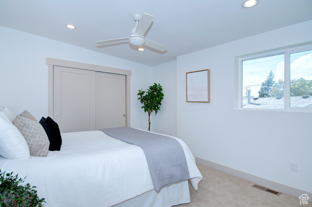 Bedroom featuring a closet, ceiling fan, and light carpet