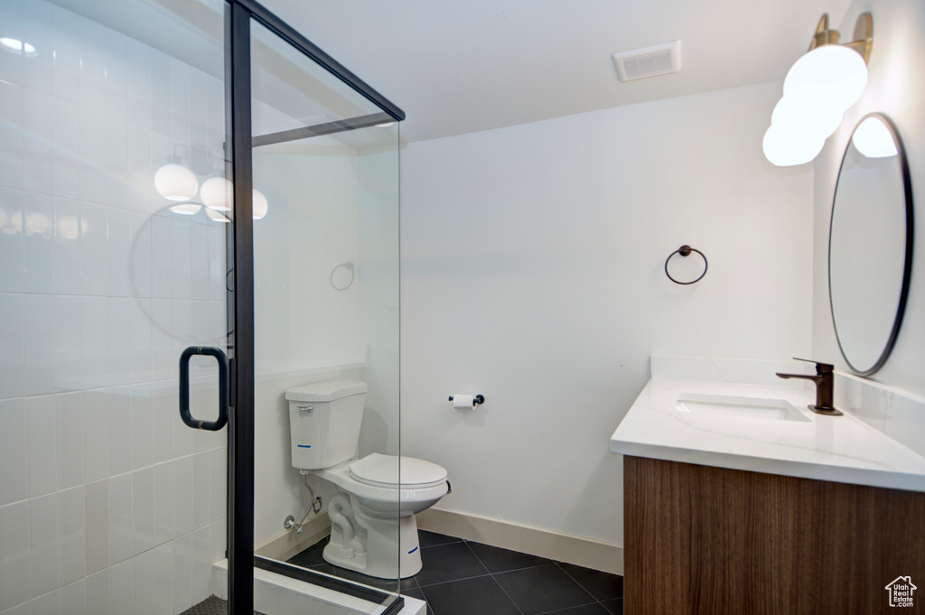 Bathroom featuring vanity, a shower with door, tile floors, and toilet
