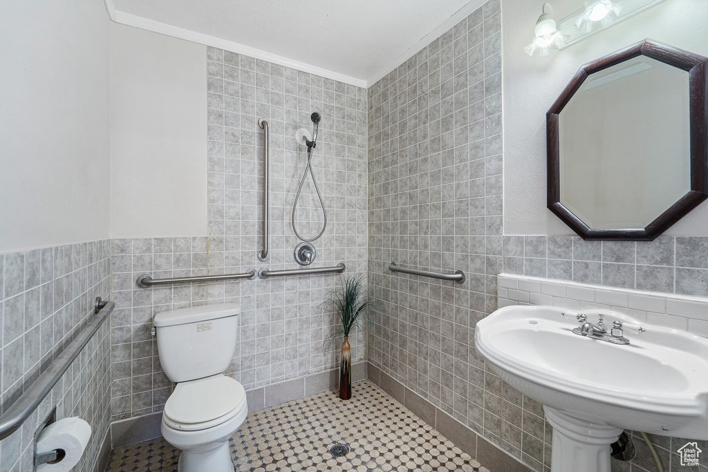 Bathroom with toilet, tile walls, ornamental molding, and tile flooring